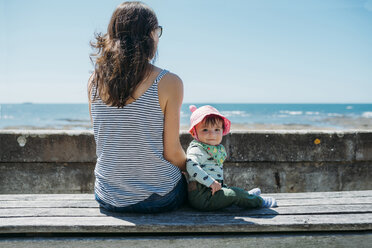 Frankreich, Mutter und kleines Mädchen sitzen auf einer Bank an der Strandpromenade - GEMF02044