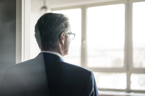 Rückansicht eines reifen Geschäftsmannes, der aus dem Fenster schaut - JOSF02205