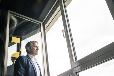 Serious mature businessman looking out of window - JOSF02219