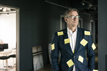 Serious mature businessman covered with sticky notes looking sideways - JOSF02221