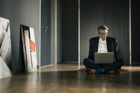 Älterer Geschäftsmann benutzt Laptop im Büro, lizenzfreies Stockfoto