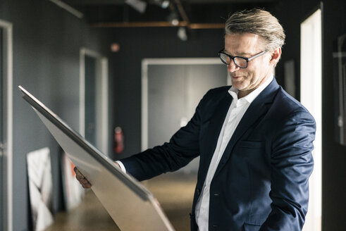 Reifer Geschäftsmann im Büro mit Blick auf ein Gemälde - JOSF02230