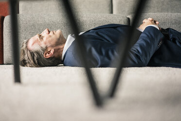 Reifer Geschäftsmann auf Teppich liegend mit geschlossenen Augen - JOSF02235