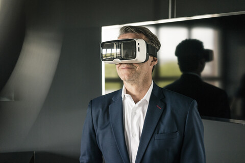 Reifer Geschäftsmann mit VR-Brille im Büro, lizenzfreies Stockfoto