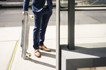 Businessman holding longboard outdoors - JOSF02245