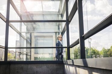 Älterer Geschäftsmann an einem Glasbau in der Stadt, der sich umschaut - JOSF02285