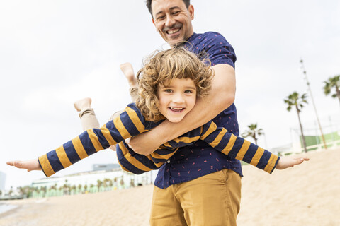 Spanien, Barcelona, Vater und Sohn spielen am Strand, lizenzfreies Stockfoto