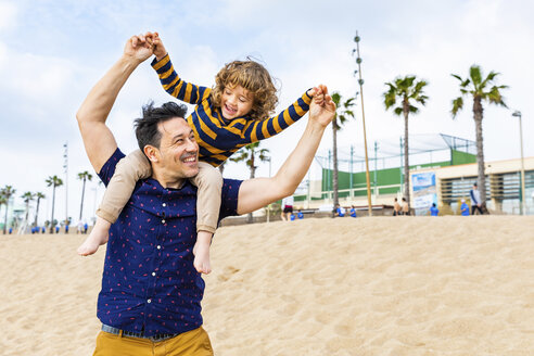 Spain, Barcelona, father with son on the beach giving a piggyback ride - WPEF00360