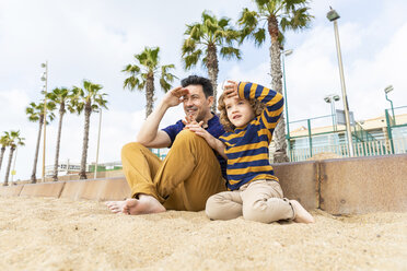 Spain, Barcelona, father and son sitting on the beach looking at distance - WPEF00370