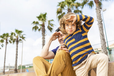 Spain, Barcelona, father and son sitting on the beach looking at distance - WPEF00371