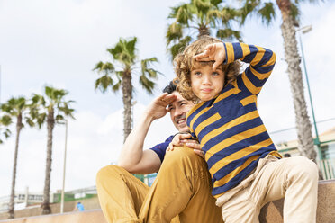 Spanien, Barcelona, Vater und Sohn sitzen am Strand und schauen in die Ferne - WPEF00371