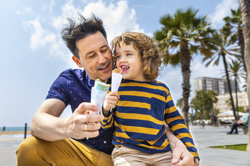 Spain, Barcelona, father and son enjoying an ice cream at seaside - WPEF00381