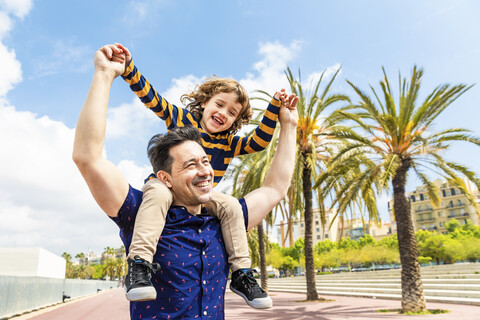 Spanien, Barcelona, glücklicher Vater, der seinen Sohn auf den Schultern trägt, lizenzfreies Stockfoto