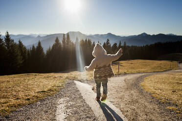 Rückansicht eines weiblichen Kleinkindes, das auf einem sonnenbeschienenen Feldweg watschelt, Tegernsee, Bayern, Deutschland - CUF15113