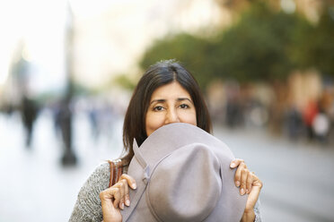 Frau hält Hut über Mund auf Straße - CUF15155