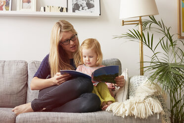 Mid erwachsene Frau und Kleinkind Tochter lesen auf Sofa - CUF15195
