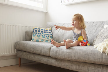 Weibliches Kleinkind spielt mit Spielzeugtrompete auf Sofa - CUF15207