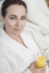 Woman relaxing at home with glass of orange juice - CUF15271
