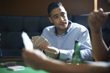 Male friends playing card game at pub card table - CUF15409