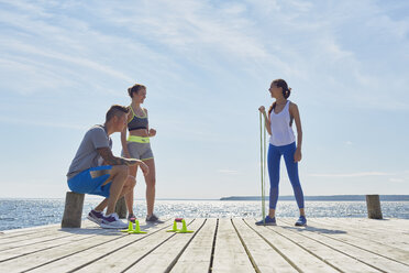 Freunde in Sportkleidung auf einem Pier mit Fitnessgeräten - CUF15424