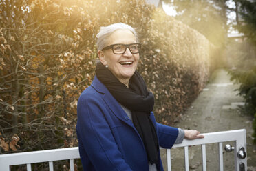 Woman opening gate looking at camera smiling - CUF15436