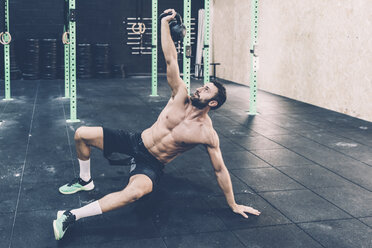 Junger männlicher Crosstrainer beim Training mit der Kettlebell im Fitnessstudio - CUF15615