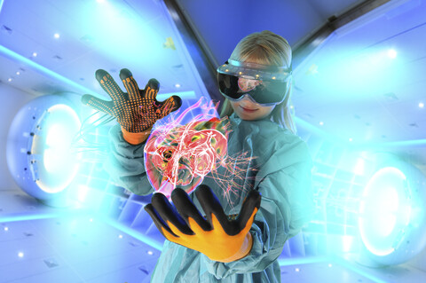 Girl in virtual reality headset interacting with digital floating human heart stock photo