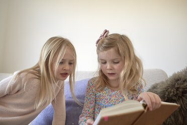 Mädchen und ihre Schwester lesen im Wohnzimmer - CUF15723