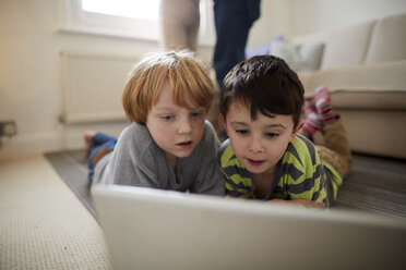 Brüder spielen Laptop-Spiel auf Zimmerteppich - CUF15729