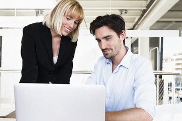 Colleagues using laptop smiling - CUF15783