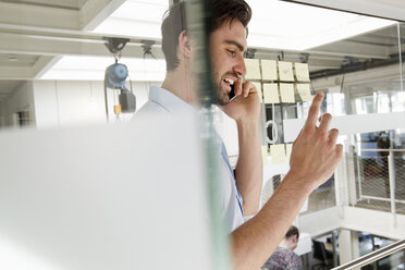 Geschäftsmann im Büro mit Mobiltelefon - CUF15786