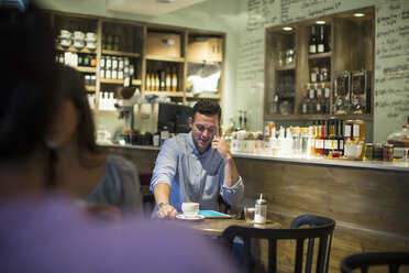 Mann sitzt im Café und spricht mit seinem Smartphone - CUF15850