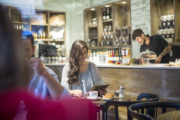 Young woman looking at digital tablet in cafe - CUF15852