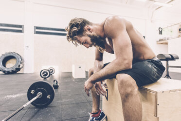 Erschöpfter männlicher Crosstrainer, der eine Pause vom Gewichtheben im Fitnessstudio macht - CUF15869