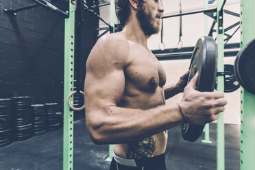 Junger männlicher Crosstrainer bei der Vorbereitung einer Langhantel im Fitnessstudio - CUF15872