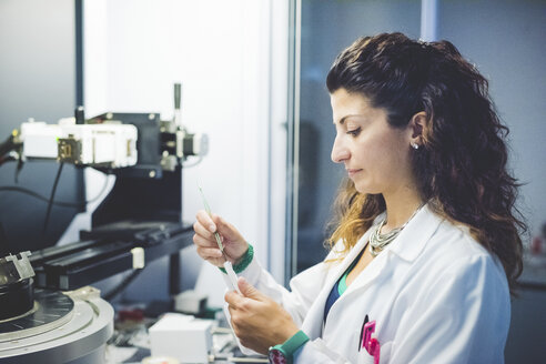 Female scientist preparing thin film sample for measurement with x-ray diffractometer - CUF15906