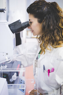 Female scientist using FTIR spectrophotometer, looking at thin film sample through FTIR microscope - CUF15912