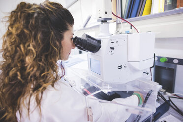 Female scientist using FTIR spectrophotometer, looking at thin film sample through the FTIR microscope - CUF15914