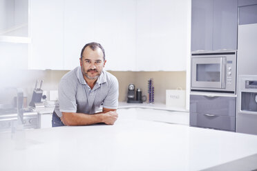 Porträt eines reifen Mannes, der sich auf die Küchentheke stützt - CUF15948