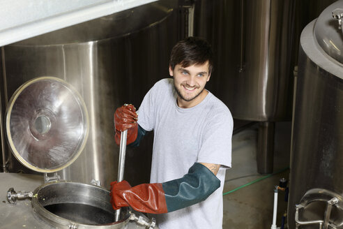 Arbeiter in der Brauerei, der Hopfen in den Sudkessel gibt - CUF16025