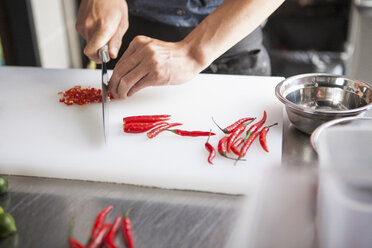 Cropped view of man slicing red chilli peppers - CUF16040