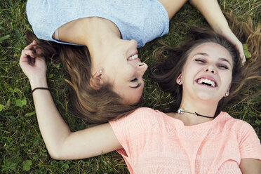 Overhead portrait of two young women lying and laughing on grass - CUF16085