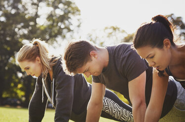 Mann und zwei Frauen beim Liegestütztraining im Park - CUF16088