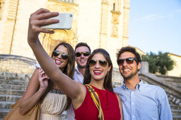 Zwei Touristenpaare mit Sonnenbrillen machen ein Selfie vor einer Kirche, Calvia, Mallorca, Spanien - CUF16104