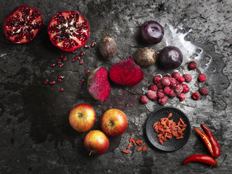 Draufsicht auf halbierte rote Früchte und Gemüse auf dunklem Hintergrund - CUF16120
