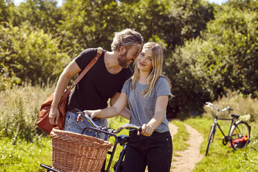 Porträt eines lachenden Paares mit Fahrrädern auf einem ländlichen Feldweg - CUF16269