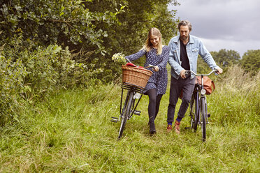 Couple pushing cycles along rural path - CUF16270