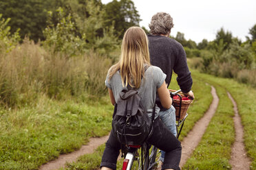 Rückansicht eines Paares beim Fahrradfahren auf einem ländlichen Feldweg - CUF16272
