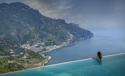 Rückansicht einer Frau, die vom Infinity-Pool auf die Küste blickt, Ravello, Amalfiküste, Italien - CUF16292