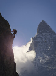 Silhouettierte Bergsteigerin beim Klettern an einer Felswand in der Nähe des Matterhorns, Kanton Wallis, Schweiz - CUF16295